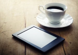 E-book reader and coffee cup on wooden table